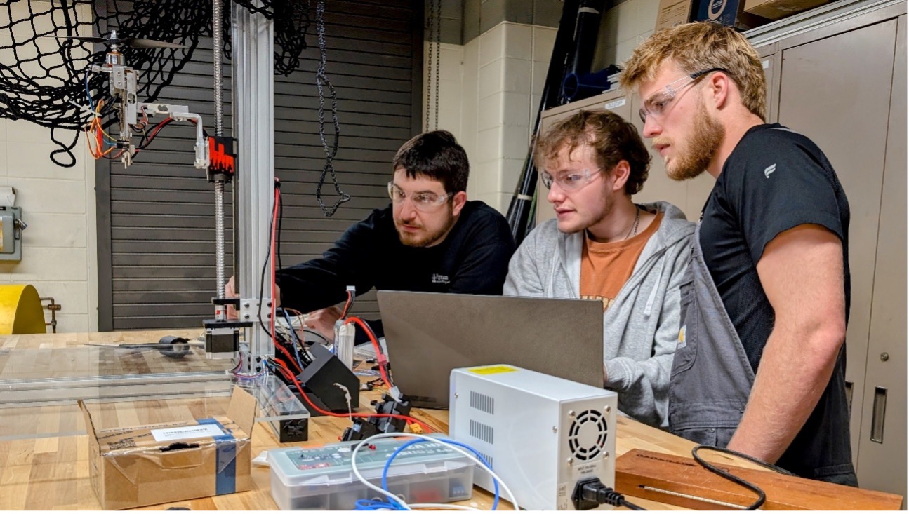 Sophomore undergraduate students Gable Rath and Cade Spurlock explain to Dr. Roghanchi how they used AI to help solve a sensor problem while designing an autonomous drone.
